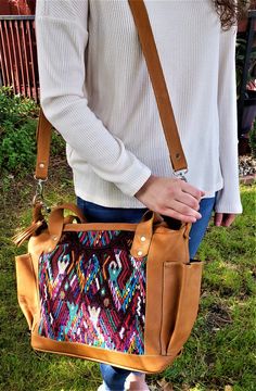 a woman carrying a colorful handbag in her right hand and standing on the grass