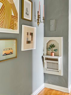 a wall with some pictures on it next to a radiator and a candle holder