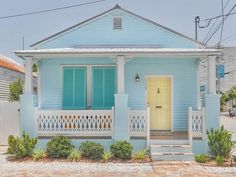 a blue house with white picket fence and yellow door on the front porch is shown