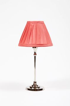 a pink lamp with a silver base and a red lampshade on the top