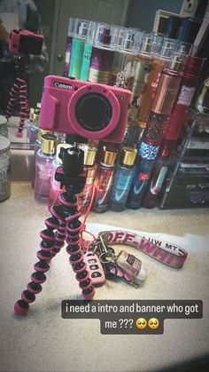 a pink camera sitting on top of a tripod in front of a pile of other items