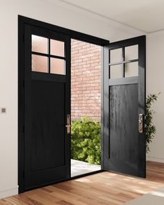 an open black door leading to a brick wall and wooden floored area with potted plants