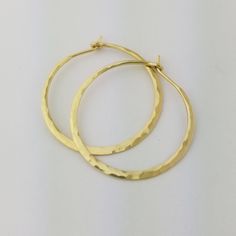 "Gorgeous Hammered Solid 18k Hoops made from 16 gauge (1.3mm) wire. 1.25\" Size photographed; 2\" size in 14k yellow gold shown in video METAL: Solid 18k Yellow Gold WIRE GAUGE/DIAMETER: 16 gauge (1.3mm) wire - Currently the thickest wire I offer EAR WIRE THICKNESS: Due to the thickness of the wire, the ear wire portion of the hoops will be tapered to approximately 18g, which is slightly thicker than standard ear wire thickness HAMMERED EFFECT: Each earring is made as a mirrored pair and the tex Yellow Gold Round Jewelry With Ear Wire, Yellow Gold Hoop Jewelry As Gift, Yellow Gold Hoop Jewelry Gift, Gift Yellow Gold Hoop Jewelry, Gold Jewelry With Ear Wire In Recycled Gold, Elegant Gold Hoop Earrings In Recycled Gold, Gift Tarnish Resistant Recycled Gold Hoop Earrings, Gift Recycled Gold Tarnish Resistant Hoop Earrings, Gold Sterling Silver Hoop Earrings For Gift