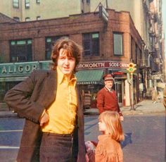 two people standing in the street with one person wearing a yellow shirt and black blazer