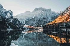 the mountains are covered in snow and reflecting in the still water at sunrise or sunset