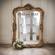 a gold framed mirror sitting on top of a wooden floor next to a vase with flowers