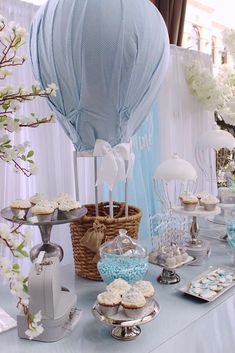 a table topped with cupcakes and desserts next to a hot air balloon