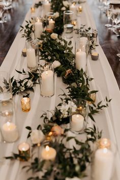 a long table with candles and greenery on it