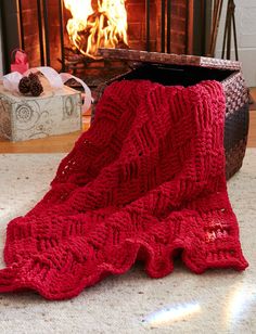 a red knitted blanket sitting on the floor next to a fire place