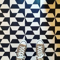 a person's feet in leopard print tennis shoes on a black and white tiled floor