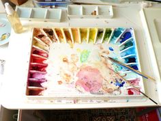 an artist's palette with watercolors and paints in it on a table