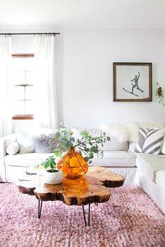 a living room filled with furniture and a wooden coffee table on top of a pink rug