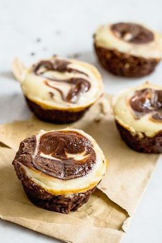 chocolate cupcakes with white frosting sitting on top of brown paper