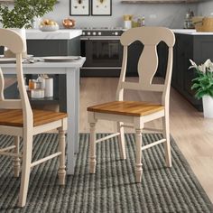 two wooden chairs sitting at a table in a kitchen next to a potted plant