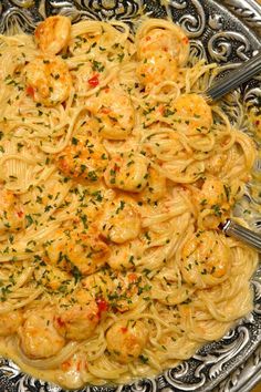 pasta with shrimp and parmesan cheese sauce in a silver bowl on a table