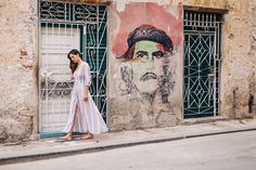 a woman standing in front of a building with a mural on it's side