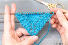 two hands are holding a crocheted triangle