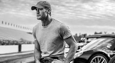 a man sitting on the hood of a sports car next to a black and white photo