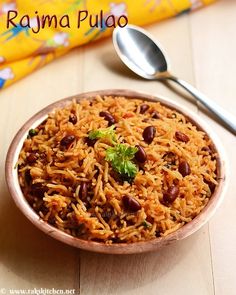 a bowl filled with rice and beans next to a spoon on top of a table