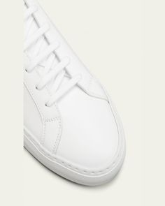 Common Projects lowtop sneaker in soft leather.    Runs large; consider ordering one size down.    1" platform heel.    Round toe.    Laceup front.    Golden embossed numbers at heel.    Rubber outsole.    "Achilles" is made in Italy. Classic White Platform Sneakers With Textured Sole, Classic Sneakers With Vulcanized Sole In Calf Leather, Classic High-top Sneakers With Vulcanized Sole, Classic Calf Leather Sneakers With Vulcanized Sole, White Low-top Platform Sneakers With Leather Sole, Classic High-top Custom Sneakers With Perforated Toe Box, Classic High-top Custom Sneakers With Perforated Toe, Calf Leather Platform Sneakers With Textured Sole, Classic White Leather Platform Sneakers