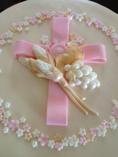 a cake decorated with flowers and a cross on the top is pink, white and gold