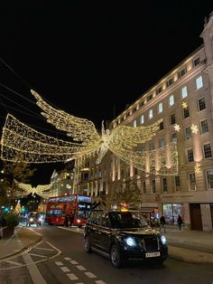 a car driving down a street with christmas lights strung across the road and buildings in the background