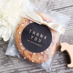 a cookie with a thank you tag on it sitting next to a white flower and a pair of scissors