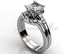 a white gold engagement ring with three stones on the side and an intricate design in the center