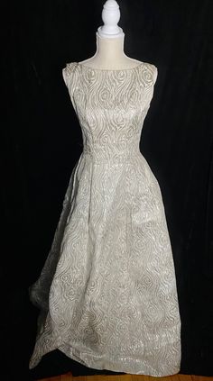 "Fabulous 1960's metallic silver and white Emma Domb formal dress with low back and high neckline. Zipper up the back and tulle under the skirt to help keep it full. Skirt near the hem has an orange spot about the size of a quarter Women's small/medium 36\" bust 27\" waist Open hips 60\" shoulder to hem" White A-line Vintage Dress For Party, Fitted Full Skirt Evening Wedding Dress, Vintage A-line Wedding Dress With Fitted Bodice, White A-line Fitted Mother Of The Bride Dress, Fitted Gown With Full Skirt For Party, White Fitted Vintage Evening Dress, Elegant Vintage Dress With Full Skirt For Party, Fitted White Vintage Evening Dress, Formal Vintage White Dress With Fitted Bodice