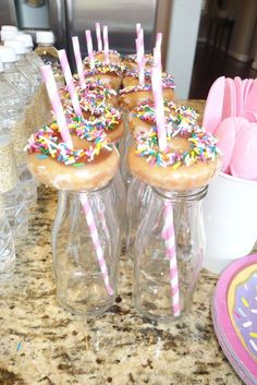 donuts with sprinkles and candles in glass vases on the counter