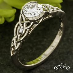 a white gold ring with a diamond in the center and an intricate band around it