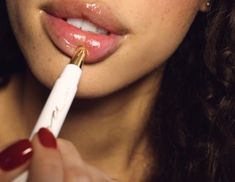 a woman brushing her teeth with an electric toothbrush in her hand and red nails on her finger