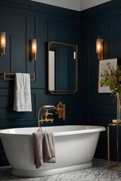 a white bath tub sitting in a bathroom next to a mirror and lights on the wall