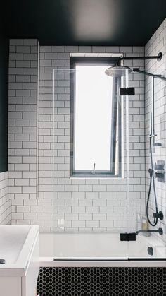 a bath tub sitting under a window next to a white sink and shower faucet