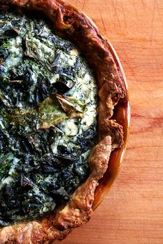 a spinach and cheese pie sitting on top of a wooden table