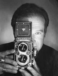 a man holding an old camera up to his face