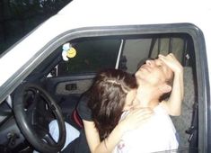 a man and woman sitting in the driver's seat of a car with their eyes closed