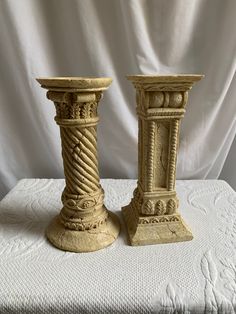 two decorative candlesticks sitting on top of a white tablecloth covered table cloth