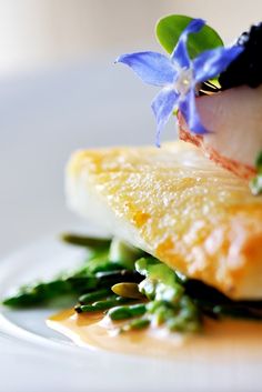 a white plate topped with food covered in sauce and flowers on top of each other