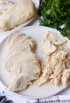 two white plates topped with sliced chicken next to parsley