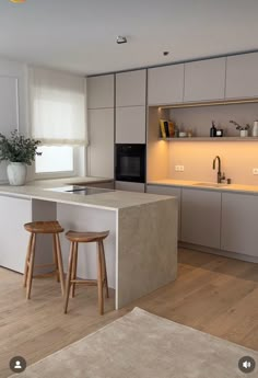 a kitchen with two stools in front of the counter and an island next to it