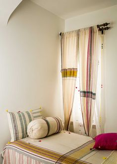 a bed sitting in a bedroom next to a window with curtains on top of it