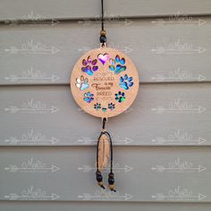 a wooden wind chime hanging from the side of a building with hearts and paw prints on it