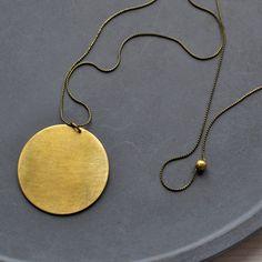 Minimalist brass necklace with circle pendant. The delicate brass snake chain without clasp is simply pulled over the head and is adorned by an approximately 4cm circle pendant made of matte polished brass. A simple hand charm that goes with any outfit. I will gladly make you a different length, just send me a message. Details - brass  - approx. 78cm long - Pendant: approx. 4cm diameter Info Brass is an alloy of copper and zinc. When tarnished, it can be restored to a high shine with a simple me Everyday Circular Brass Necklace, Everyday Brass Necklace, Minimalist Adjustable Medallion Necklace, Adjustable Brass Necklace With Hammered Detail, Hammered Brass Round Necklaces, Hammered Brass Necklace With Round Pendant, Everyday Brass Round Necklace, Minimalist Brass Jewelry With Large Pendant, Minimalist Adjustable Brass Necklace