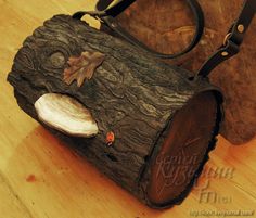 a bag made out of wood with leaves and acorns on the inside, sitting on a wooden surface