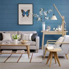 a living room with blue walls and white flowers in vases on the coffee table