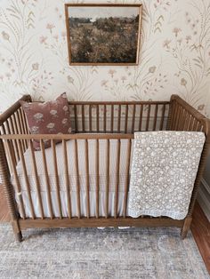 a baby crib in front of a wall with a painting on it's side