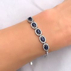 This breathtaking genuine blue sapphire and white topaz bracelet makes a gorgeous gift or a decadent treat just for you. The beautiful deep blue of the the sapphire creates a striking contrast to the sparkling white topaz stones surrounding them. Set in 925 sterling silver with an anti tarnish platinum finish, it looks sparkling and luxurious on your wrist. Measures 6 &3/4''  in length with a 2'' silver extension and sapphire stones measure approximately 6 mm by 4 mm and oval stone with white topaz surround measure 8 mm by 10 mm Available in genuine emerald and ruby stones. September birthstone. 45th Wedding Anniversary Gemstone Sapphire often contain inclusions. These flaws are not looked upon as negative attributes.  Indeed, these inclusions are considered part of the character of the st Sapphire Cubic Zirconia Diamond Bracelet For Anniversary, Sapphire Color Cubic Zirconia Diamond Bracelet Gift, Sapphire Bracelet With Diamond Accents As Gift, Anniversary Sapphire Diamond Bracelet In Cubic Zirconia, Sapphire Bracelets With Diamond Accents As Gift, Sapphire Cubic Zirconia Fine Jewelry Bracelets, Sapphire Cubic Zirconia Bracelets Fine Jewelry, Sapphire Cubic Zirconia Tennis Bracelet With Gemstone, Fine Jewelry Sapphire Bracelets With Cubic Zirconia