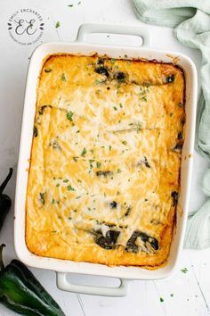 a casserole dish with cheese and black olives in it on a white surface