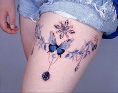 a woman's thigh with blue butterflies and chains on the side, tattoo style